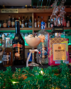 The Baileys Gingerbread Martini on a home bartop surrounded by its ingredients 