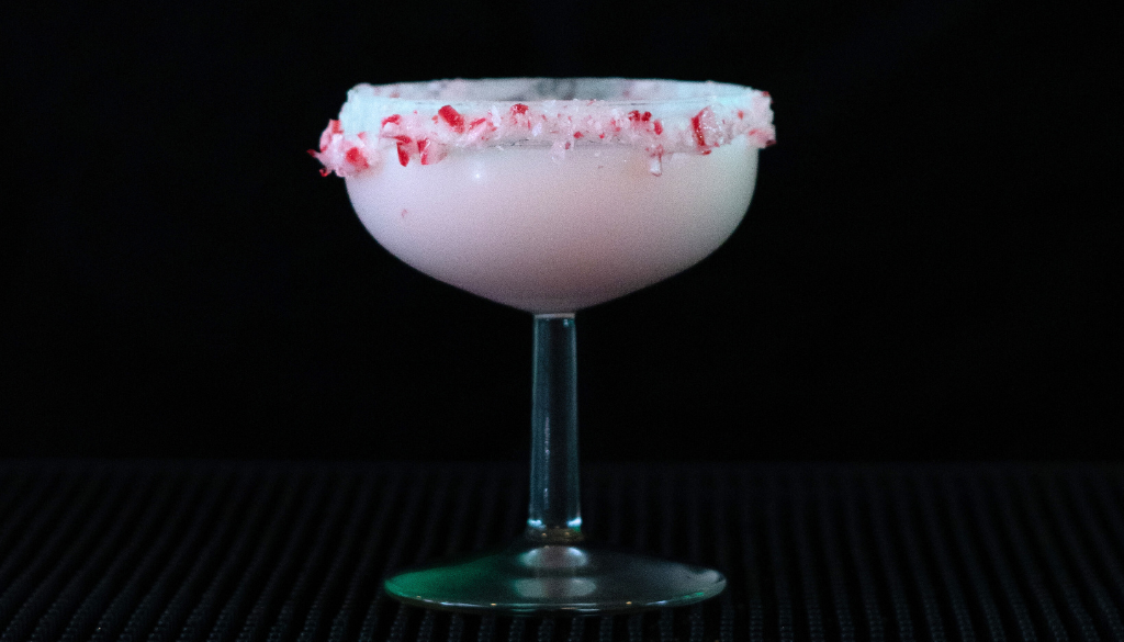 The candy cane martini on a home bartop with a black background