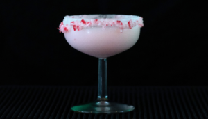 The Candy Cane Martini on a home bar top with a black background.