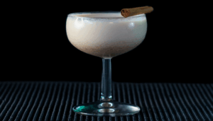 The Eggnog Martini on a bar top wit a black background.