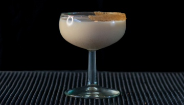 The Spiced Eggnog Martini on a bar top with a black background