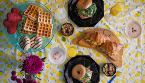 Brunch with Brunch Cocktails including Pisco Sour, Cappuccino Martini, Mimosa and Elderflower Collins with croissants, waffles, donuts and a salmon bagel on a lemon tablecloth 