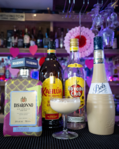 The P.S. I Love You cocktail on a home bar top, surrounded by its ingredients