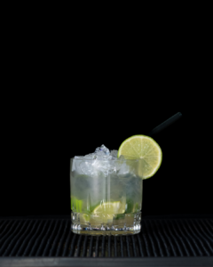 The caipiroska cocktail on a home bar top with an all black background