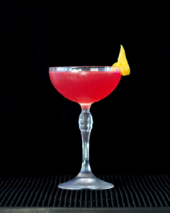 The Cosmopolitan cocktail on a home bar top with an all black background