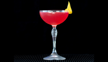 The Cosmopolitan cocktail on a home bar top with an all black background