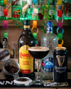 The Guinness Espresso Martini cocktail on a home bar top surrounded by its ingredients