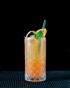 The pot of gold mocktail on a home bar top with an all black background
