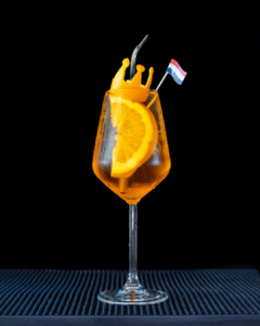 The Kingsday Spritz cocktail on a home bar top with an all black background