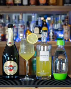 The Limoncello Spritz cocktail on a home bar top, surrounded by its ingredients