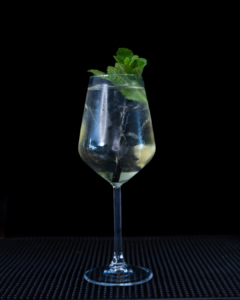 The Lychee Spritz cocktail on a home bar top with an all black background