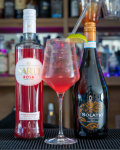 The Sarti Spritz Cocktail on a home bar surrounded by its ingredients
