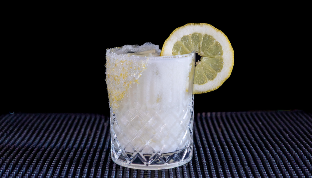 The Creamy Limoncello Margarita cocktail on a homebar top, with an all black background