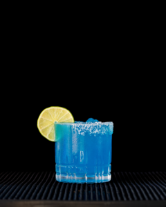 The Margarita Azul cocktail on a homebar top, with an all black background