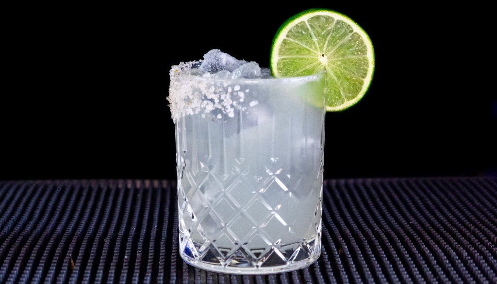 The Mezcal Margarita cocktail on a homebar top with an all black background