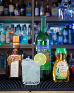 The Mezcal Margarita cocktail on a home bar top surrounded by its ingredients