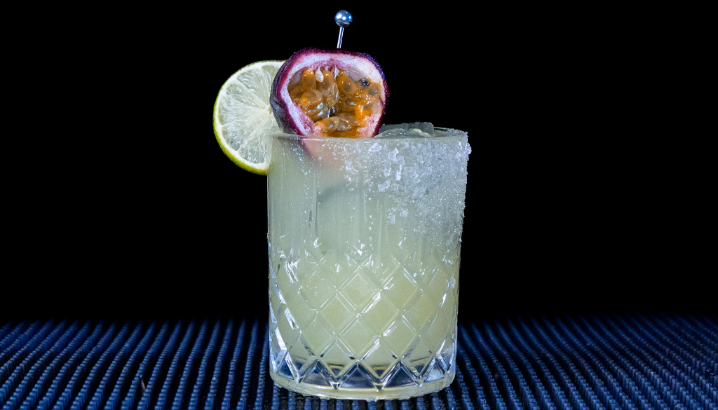 The Passionfruit Margarita cocktail on a home bar top with an all black background