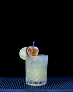 The Passionfruit Margarita cocktail on a home bar top with an all black background