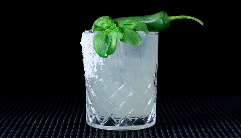The Spicy Basil Margarita cocktail on a homebar top with an all black background