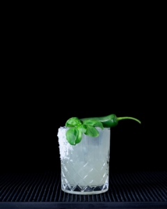 The Spicy Basil Margarita cocktail on a homebar top with an all black background