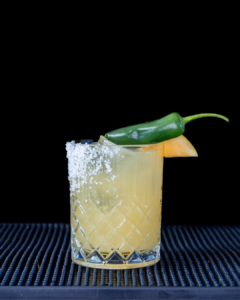 The Spicy Mango Margarita cocktail on a homebar top, with an all black background
