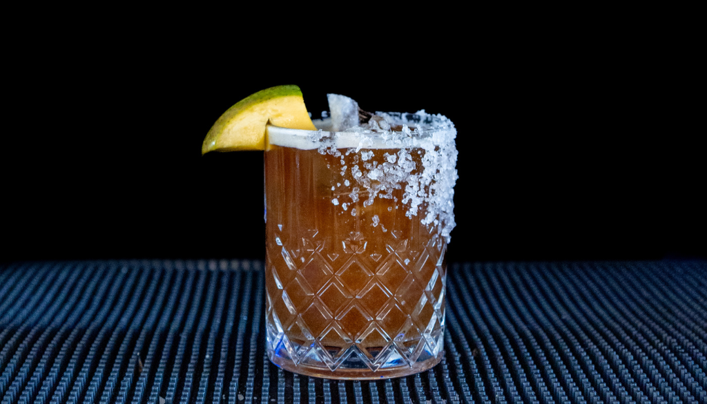 The Tropical Coffee Margarita cocktail on a home bar top with an all black background