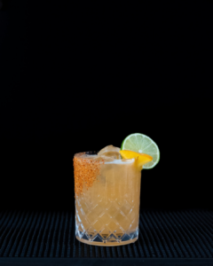 The Hot Honey Peach Margarita cocktail on a home bar top with an all black background