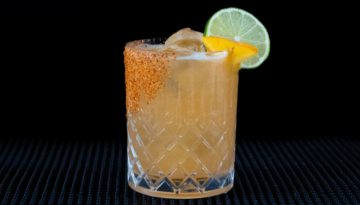 Hot Honey Peach Margarita cocktail on a home bar top with an all black background