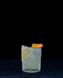 The Mallorcan (orange) Margarita cocktail on a home bar top with an all black background