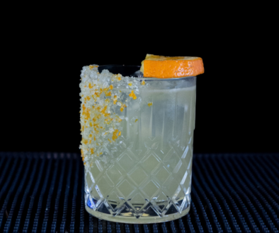 The Mallorcan (orange) Margarita cocktail on a home bar top with an all black background