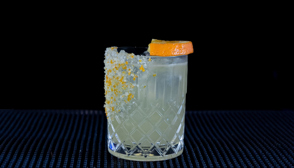 The Mallorcan (orange) Margarita cocktail on a home bar top with an all black background