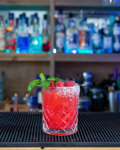 Hot Raspberry Basil Margarita cocktail on a home bar top with an all black background
