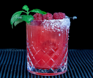 The Raspberry Basil Margarita cocktail on a home bar top with an all black background